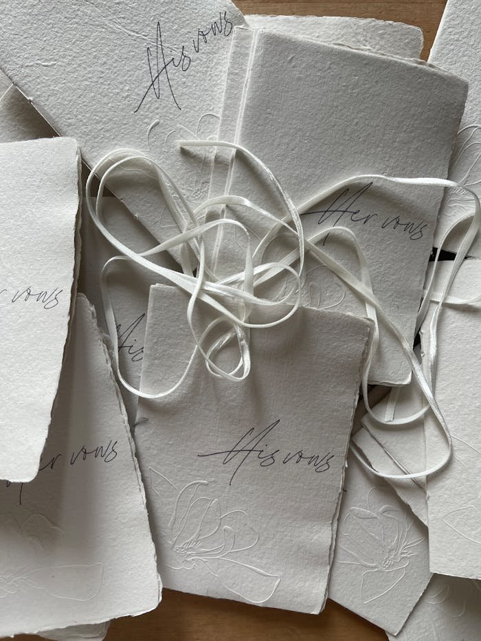 Top view of handcrafted invitations with ribbons on textured paper, perfect for weddings and events.