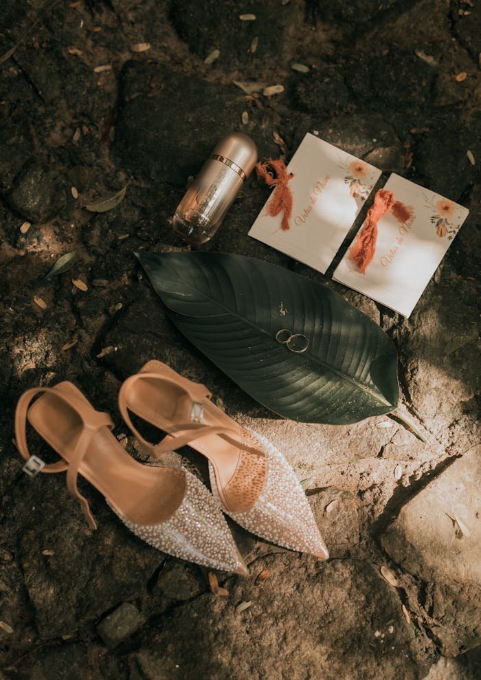 Charming flat lay of wedding shoes, invitations, and rings on a rustic background.